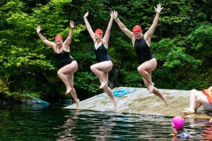 Three people in swimsuits leaping into the water
