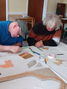 Two people doing art at a table at the art workshop
