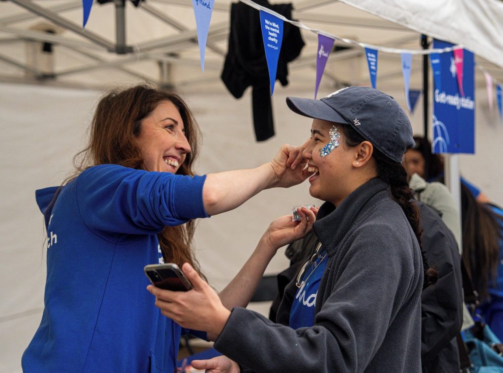 A female putting face paint onto another person.