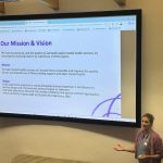 A person standing up doing a powerpoint presentation
