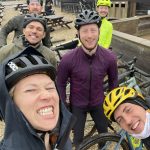 A few people smiling at the camera with their bikes