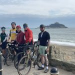 A group of cyclists with Marazion behind them