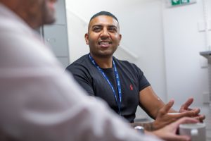 A person wearing a Mind lanyard smiling at another person
